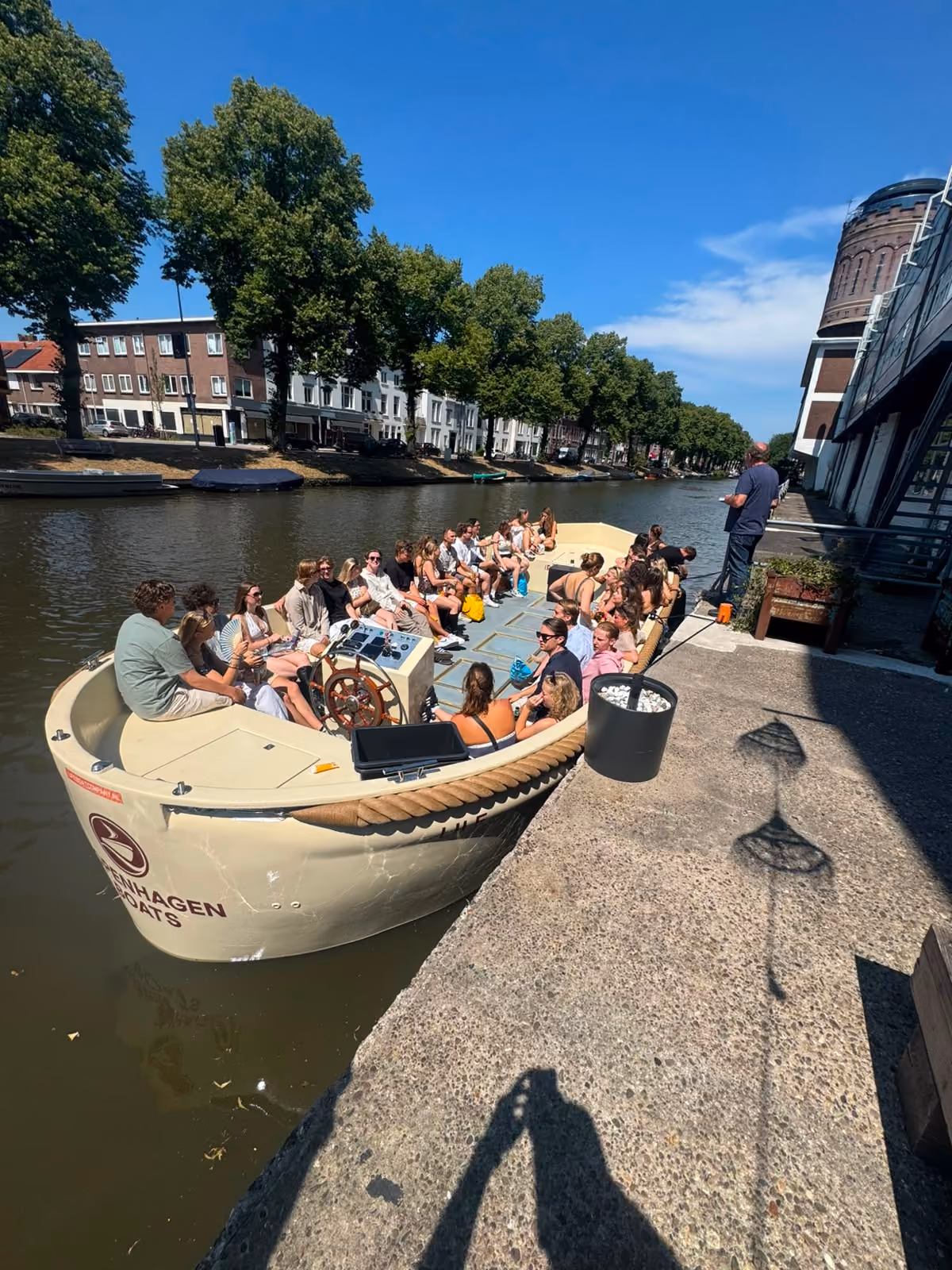 Large group seated on a Copenhagen Boats open boat moored at a canal quay